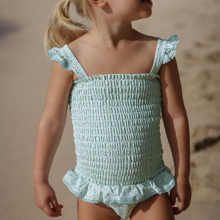 little girl wearing minnow swim smocked one piece